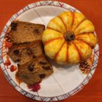 a small pumpkin next to pieces of sliced pumpkin bread