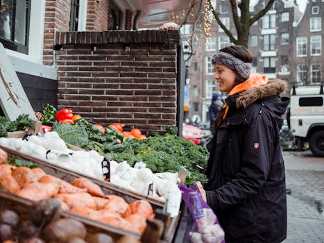 A young woman shops for fresh vegetables at an outdoor urban farmer's market in winter.